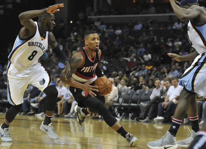 Portland Trail Blazers guard Damian Lillard (0) drives to the basket against Memphis Grizzlies forward James Ennis (8) and Memphis Grizzlies forward Zach Randolph (50) during the first half  at FedExForum.