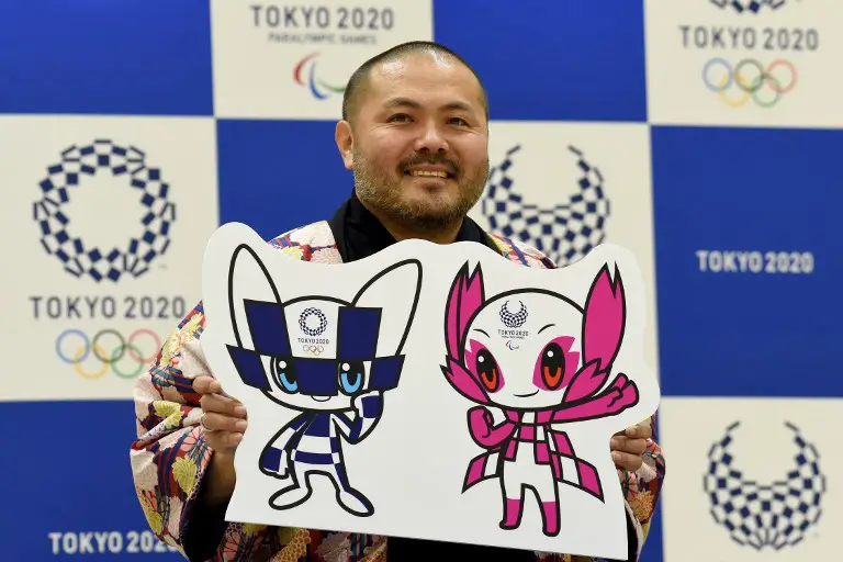 Ryo Taniguchi, winning designer of the official mascots for the 2020 Olympics (L) and Paralympics Games, poses for photographers at an elementary school in Tokyo on February 28, 2018.
Tokyo on February 28 unveiled its long-awaited mascot for the 2020 Olympic Games: a futuristic blue-checked, doe-eyed character with pointy ears and "special powers" that was picked by schoolchildren across mascot-mad Japan. / AFP PHOTO / TORU YAMANAKA