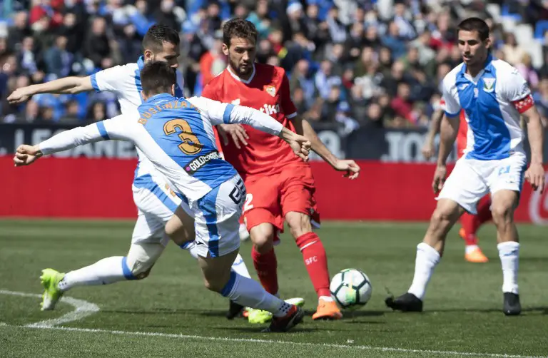 Sevilla's Italian midfielder Franco Vazquez (C) vies with Leganes' Spanish defender Unai Bustinza (L) during the Spanish League football match between Club Deportivo Leganes SAD and Sevilla FC at the Estadio Municipal Butarque in Leganes on March 18, 2018. / AFP PHOTO / CURTO DE LA TORRE