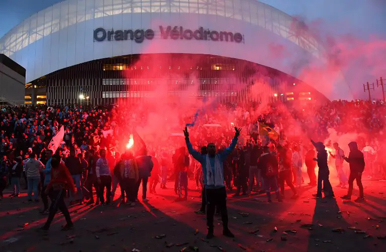 Marseille's supporters burn flares on March 18, 2018, in front of the Velodrome Stadium in Marseille, southeastern France, before the French L1 football match between Marseille (OM) and Lyon (OL). / AFP PHOTO / ANNE-CHRISTINE POUJOULAT