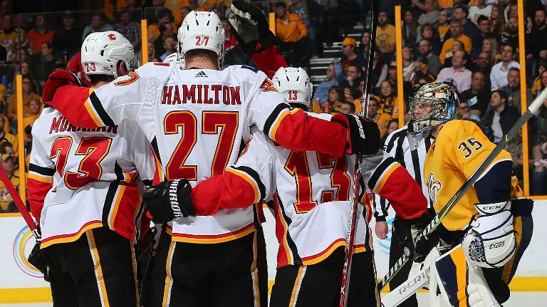 NASHVILLE, TN - FEBRUARY 15: Sean Monahan #23, Michael Stone #26, and Johnny Gaudreau #13 of the Calgary Flames celebrate a goal against goalie Pekka Rinne #35 of the Nashville Predators during the second period at Bridgestone Arena on February 15, 2018 in Nashville, Tennessee.   Frederick Breedon/Getty Images/AFP