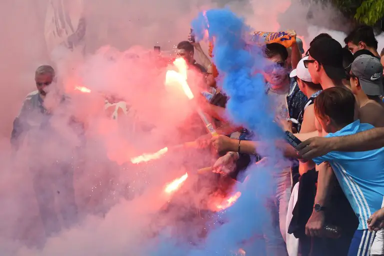 Marseille supporters burn flares and cheer as they gather to attend the team's training session at the Robert-Louis Dreyfus training center on May 2, 2018 in Marseille on the eve of the Europa League semi-final second round football match between Olympique de Marseille and Salzburg.  / AFP PHOTO / Boris HORVAT