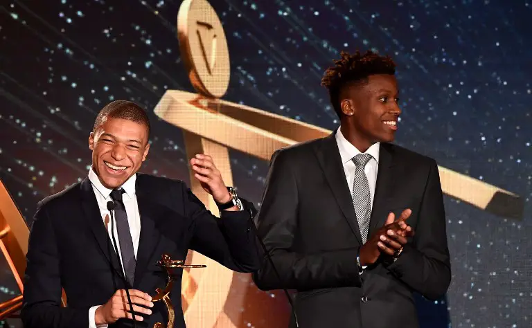 Paris Saint-Germain's French forward Kylian Mbappe (L) receives the best hope player trophy during during a TV show on May 13, 2018 in Paris, as part of the 27th edition of the UNFP (French National Professional Football players Union) trophy ceremony. / AFP PHOTO / FRANCK FIFE