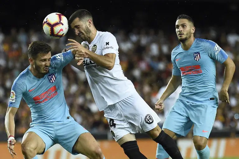 Valencia's Spanish defender Jose Luis Gaya Pena (C) heads the ball with Atletico Madrid's Spanish midfielder Saul Niguez next to Atletico Madrid's Spanish midfielder Koke (R) during the Spanish League football match between Valencia and Atletico Madrid at the Mestalla Stadium in Valencia on August 20, 2018. / AFP PHOTO / JOSE JORDAN