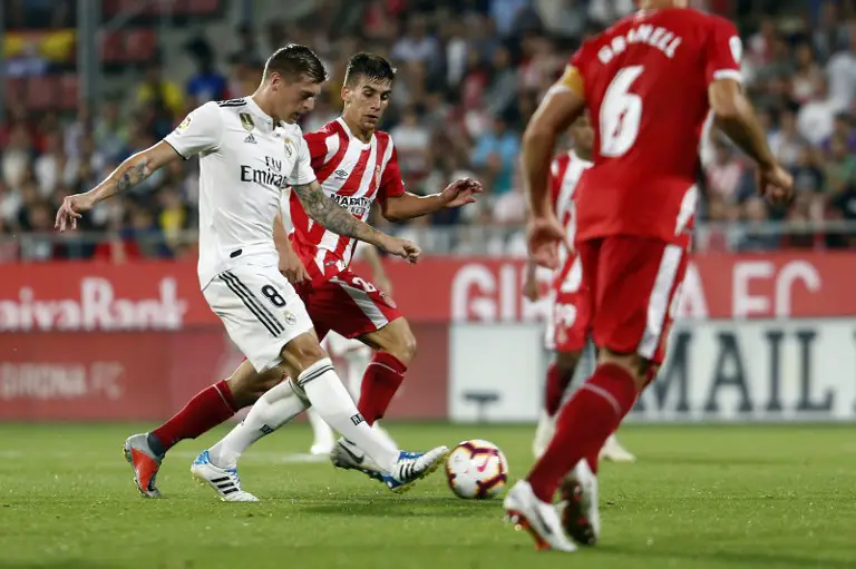 Real Madrid's German midfielder Toni Kroos (L) vies with Girona's Spanish midfielder Pere Pons during the Spanish league football match between Girona FC and Real Madrid CF at the Montilivi stadium in Girona on August 26, 2018. / AFP PHOTO / Pau BARRENA CAPILLA