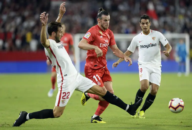 Real Madrid's Welsh forward Gareth Bale (C) vies with Sevilla's Italian midfielder Franco Vazquez (L) during the Spanish league football match Sevilla FC against Real Madrid CF at the Ramon Sanchez Pizjuan stadium in Seville on September 26, 2018. / AFP PHOTO / CRISTINA QUICLER