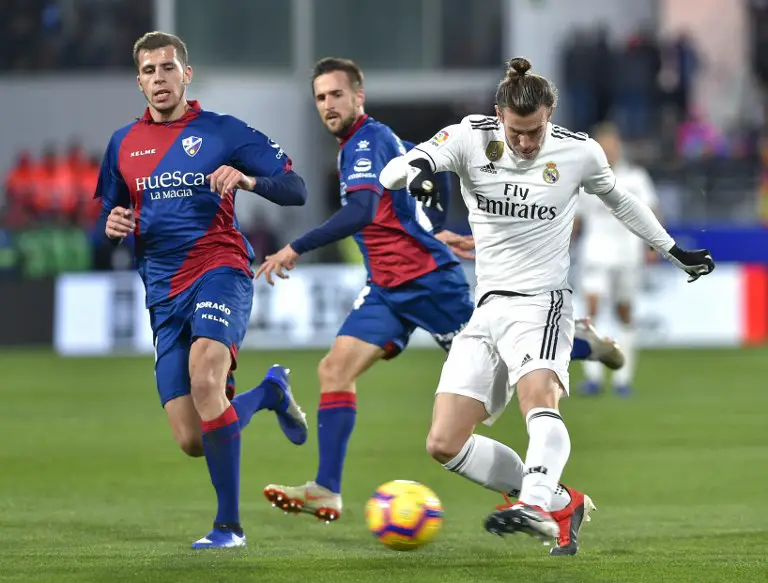 Real Madrid's Welsh forward Gareth Bale (R) kicks the ball during the Spanish league football match between SD Huesca and Real Madrid CF at the El Alcoraz stadium in Huesca, on December 9, 2018. (Photo by ANDER GILLENEA / AFP)