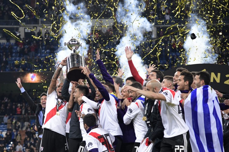 Players of River Plate celebrate with the trophy after winning the second leg match of the all-Argentine Copa Libertadores final against Boca Juniors, at the Santiago Bernabeu stadium in Madrid, on December 9, 2018. (Photo by Javier SORIANO / AFP)