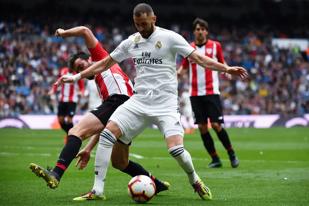 Real Madrid's French forward Karim Benzema (R) challenges Athletic Bilbao's Spanish defender Inigo Lekue during the Spanish League football match between Real Madrid and Athletic Bilbao at the Santiago Bernabeu Stadium in Madrid on April 21, 2019. (Photo by GABRIEL BOUYS / AFP)