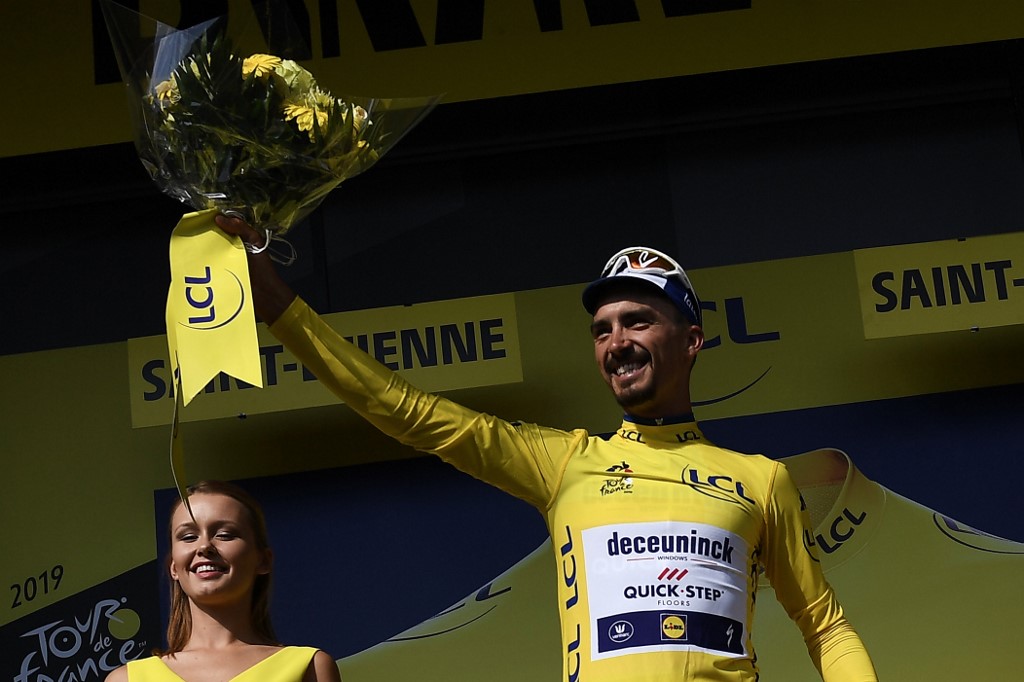 France's Julian Alaphilippe (R) celebrates his overall leader's yellow jersey on the podium of the eighth stage of the 106th edition of the Tour de France cycling race between Macon and Saint-Etienne, in Saint-Etienne, eastern France, on July 13, 2019. (Photo by JEFF PACHOUD / AFP)