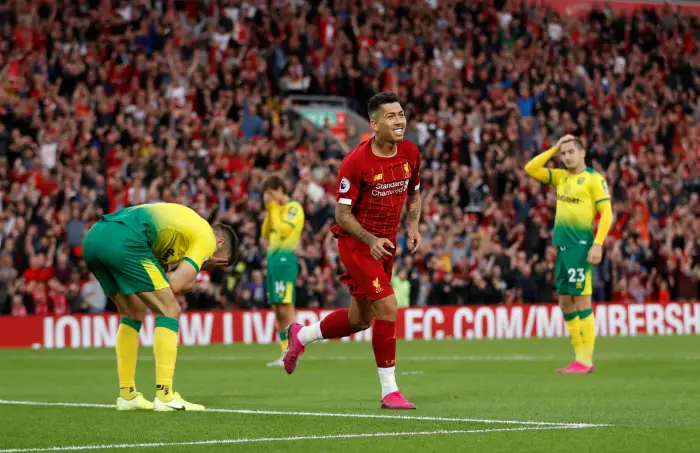 Norwich City's Grant HanHy lookHdejected after scoring Liverpool's first goal with an own goal while Liverpool's Roberto Firmino celebrates