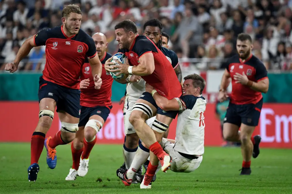 England's back row Mark Wilson (C) is tackled by US fly-half AJ MacGinty (2R)  during the Japan 2019 Rugby World Cup Pool C match between England and the United States at the Kobe Misaki Stadium in Kobe on September 26, 2019. (Photo by Filippo MONTEFORTE / AFP)