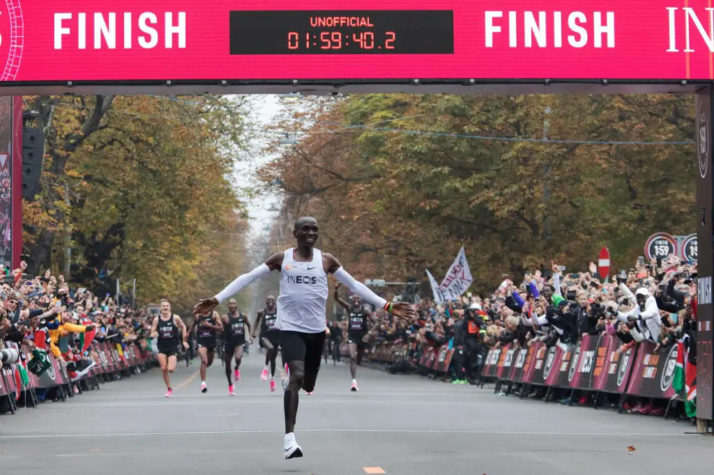 Kenya's Eliud Kipchoge (white jersey) celebrates as he crosses the finish line at the end of his attempt to bust the mythical two-hour barrier for the marathon on October 12 2019 in Vienna. - Kenya's Eliud Kipchoge on Saturday made history, busting the mythical two-hour barrier for the marathon on a specially prepared course in a huge Vienna park.
With an unofficial time of 1hr 59min 40.2sec, the Olympic champion became the first ever to run a marathon in under two hours in the Prater park with the course readied to make it as even as possible. (Photo by ALEX HALADA / AFP)