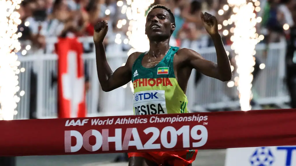 Ethiopia's Lelisa Desisa celebrates as he crosses the finish line and wins the Men's Marathon at the 2019 IAAF Athletics World Championships in Doha in the night between October 5, 2019 and October 6, 2019. (Photo by MUSTAFA ABUMUNES / AFP)