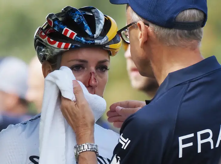 France's cyclist Pauline Ferrand Prevot (L) receives a first aid from a team officer during the Ready Steady Tokyo Cycling Mountain Bike women's cross-country event in Izu, Shizuoka prefecture on October 6, 2019. (Photo by Toshifumi KITAMURA / AFP)