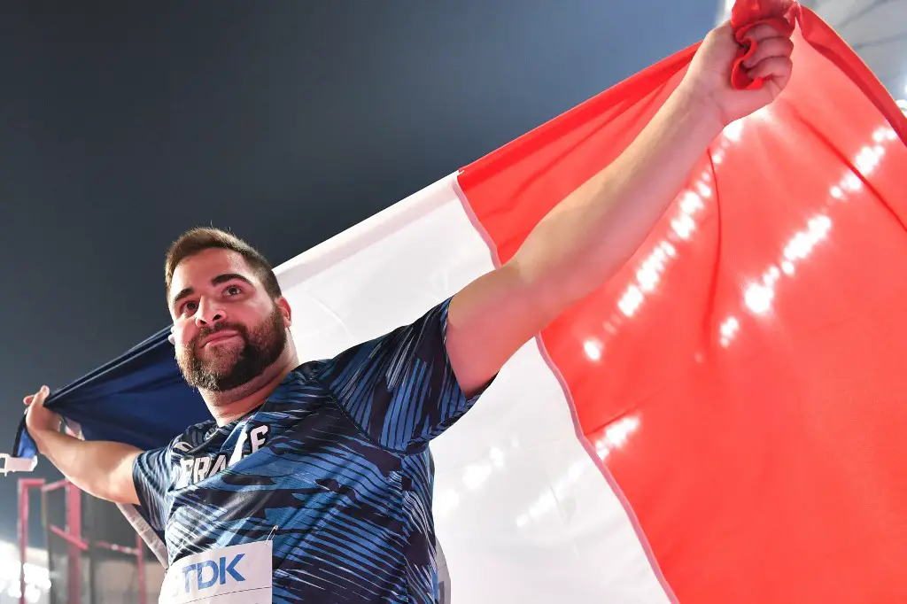 France's Quentin Bigot holds the national flag after finishing second in the Men's Hammer Throw final at the 2019 IAAF Athletics World Championships at the Khalifa International stadium in Doha on October 2, 2019. (Photo by ANDREJ ISAKOVIC / AFP)