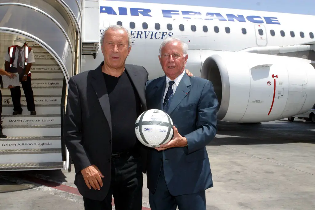 Michel Hidalgo, former coach of the French national team (R), and Henri Biancheri, general manager of the French football club AS Monaco, pose in front of a French passenger plane at Doha airport 17 June 2004 for the "kick off" of the first Doha-Paris Air France flight. AFP PHOTO/Karim JAAFAR (Photo by KARIM JAAFAR / AFP)