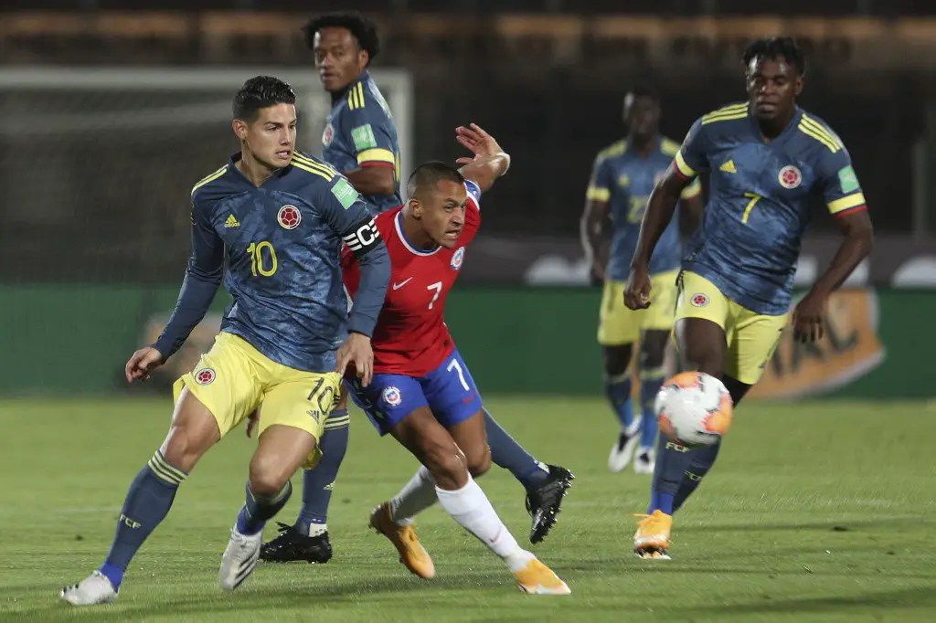 Colombia's James Rodriguez (L) and Chile's Alexis Sanchez (C) vie for the ball during their 2022 FIFA World Cup South American qualifier football match at the National Stadium in Santiago, on October 13, 2020, amid the COVID-19 novel coronavirus pandemic. (Photo by Esteban Felix / POOL / AFP)