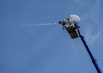 15 August 2021, Hessen, Frankfurt/Main: In calm and sunshine, a cameraman with a parasol stands at a lofty height on the platform of a mobile crane. From there he offers a television perspective of the European Triathlon Championship, the Ironman Frankfurt, which is taking place down on the Main. On the left, a commercial aircraft is flying in the blue sky above the city. Photo: Frank Rumpenhorst/dpa 
By Icon Sport - Francfort (Allemagne)