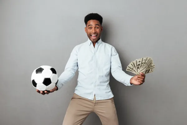 Homme africain souriant tenant un ballon de football et des billets de banque